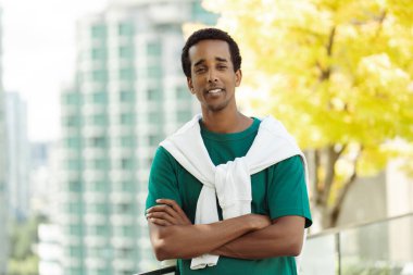 Yakışıklı, gülümseyen, Afro-Amerikan bir adam parkın içinde kameraya bakıyor. Üniversite kampüsünün yanında duran çekici genç öğrenci, reklam, eğitim konsepti 