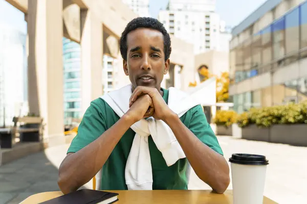 Portrait of pensive attractive African American man sitting at workplace, having video conference, listening to online lesson, watching video. Attractive student preparing for exam. Concept of online education
