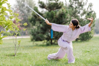 Kafkas kadın sabah parkta Tai Chi kılıcıyla çalışıyor. Çin dövüş sanatları, yaşam konsepti için sağlıklı bakım