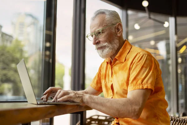 英俊的老人 在现代咖啡馆里使用笔记本电脑在线工作的程序员 时尚商人计划创业 搜索网站上的信息 成功的商业概念 — 图库照片