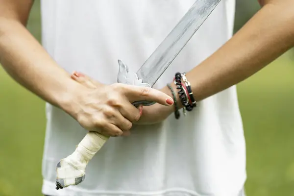 Cropped view of the martial arts woman holding sword for wushu kungfu while standing at green park. Healthy wellness active training concept