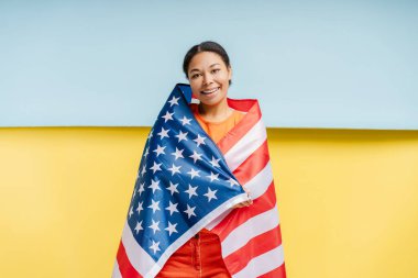 Amerikan bayrağına sarılmış, kendinden emin gülümseyen Afro-Amerikan kadın portresi Ukrayna bayrağına sarılmış. Destek konsepti 
