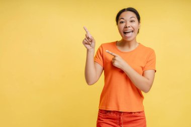Çekici özgüvenli Afro-Amerikan kadın portresi sarı arka plan fotokopi alanında izole edilmiş bir parmak işaret ediyor. Gülümseyen, gülümseyen, kameraya bakan, reklam için poz veren kadın.