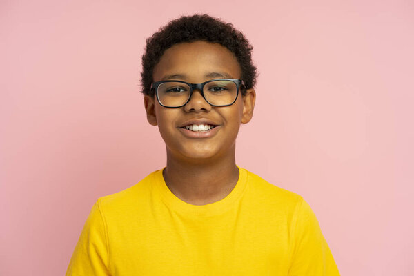 Smiling school boy wearing stylish eyeglasses isolated on pink background. Education concept