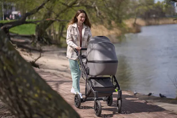 Young Woman Loving Mother Pushing Gray Baby Stroller Slowly Walking — Stock Photo, Image