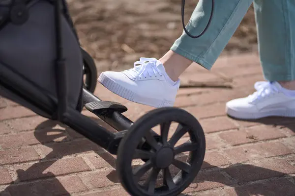 Kadın Ayağının Ayrıntıları Dışarıda Dolaşırken Modern Bebek Arabasının Fren Pedalında — Stok fotoğraf