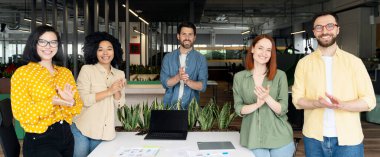 Çok yönlü ofis çalışanlarından, girişimcilerden, yaratıcı tasarımcılardan, masa başında duran satış müdürlerinden oluşan başarılı bir ekip el çırpıyor, gülümsüyor kameraya güvenle bakıyor.