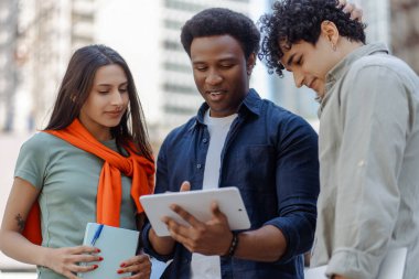 Tablet kullanan, girişimi planlayan, sokakta video izleyen çok uluslu yakışıklı insanlar. Takım çalışması konsepti