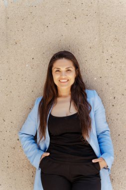 Orta yaşlı mutlu iş kadınının dikey görüntüsü. Dışarıdaki kameraya bakıyor, mekanı kopyalıyor. Sokakta duran mavi takım elbiseli kendine güvenen bir kadının portresi. 