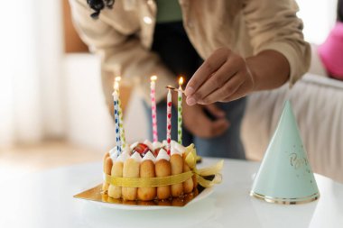 Seçici odak, yakın plan Afro-Amerikan kadın doğum günü pastasında mum üfleyen doğum günü kızı evde otururken dilek tutuyor. Kutlama konsepti