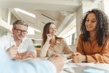 Bir grup güler yüzlü iş adamı, iş arkadaşları konuşuyor, plan yapıyor, fikirleri paylaşıyor modern ofiste birlikte çalışıyorlar. Buluşma, takım çalışması, başarılı iş, kariyer konsepti 