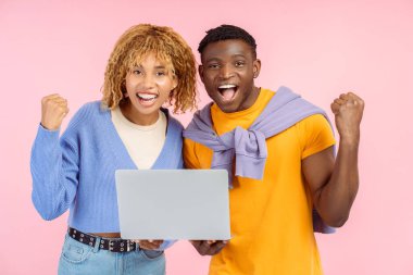 Dizüstü bilgisayar kutlaması yapan birkaç gülümseyen arkadaş pembe arka planda izole edilmiş. Aşırı neşeli Afrikalı Amerikalı erkek ve kadın internetten kameraya bakıyor. Teknoloji