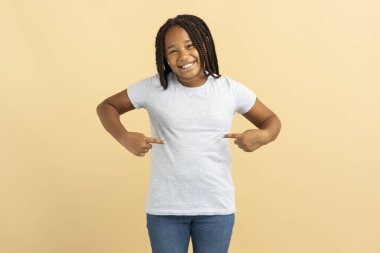 Gri tişörtlü gülümseyen küçük Afro-Amerikan kız kendini soyutlamış. Model