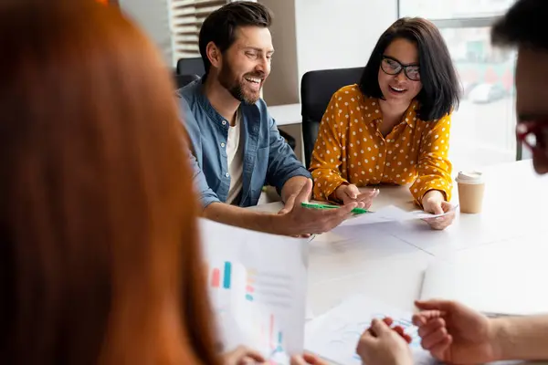Mutlu gülümseyen işadamı, modern kurumsal ofis içlerindeki konferans odasında otururken iş arkadaşlarıyla yeni proje ve iş stratejisini tartışıyor. Halkın Çeşitliliği Kariyer Takım Çalışması