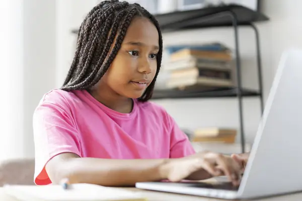 キーボードにピンクのTシャツを入力し タスクを行い 言語を学習し 自宅で試験を受ける準備をしている深刻なアフリカ系アメリカ人の少女の肖像画 オンライン教育の概念 — ストック写真