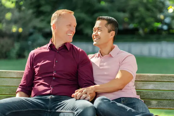 Pareja Gay Sonriente Mediana Edad Abrazándose Mirándose Tomándose Mano Sentados —  Fotos de Stock