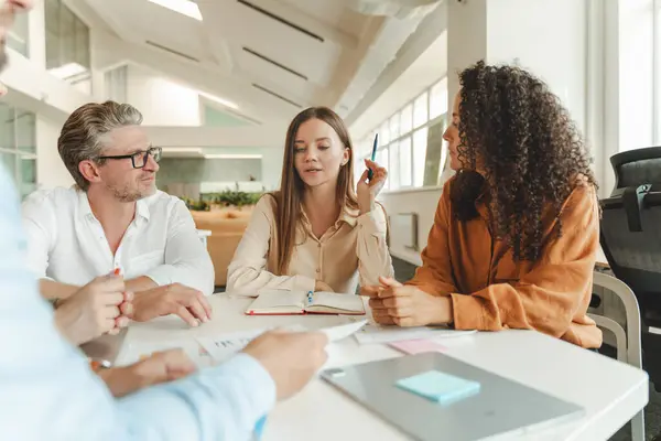 stock image Confident businesswoman sitting at workplace working with colleagues, brainstorming, sharing ideas in modern office. Teamwork, meeting, startup concept