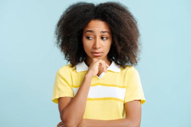 Heyecanlı, kıvırcık saçlı, mavi arka planda izole edilmiş güzel Afro-Amerikan kadın portresi. Reklam kavramı