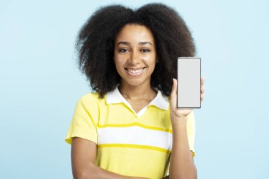 Güzel gülümseyen Afro-Amerikan kadın cep telefonuyla mavi arka planda izole edilmiş dijital ekranı gösteriyor. Satış, online alışveriş, Kara Cuma konsepti.