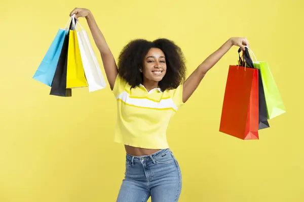 Sarı Arka Planda Renkli Alışveriş Torbaları Tutan Mutlu Afro Amerikan — Stok fotoğraf