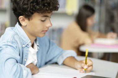 Düşünceli zeki genç çocuk notlar alıyor, dil öğreniyor, sınav hazırlığı yapıyor, modern sınıfta kitap okuyor. Okula dönmek, eğitim kavramı. 