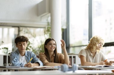 Akıllı gülümseyen ergen öğrenci sınıfta otururken soruyu cevaplıyor. Bir grup genç birlikte okuyorlar, dil öğreniyorlar, modern kütüphanede sınav hazırlığı yapıyorlar. Eğitim kavramı 