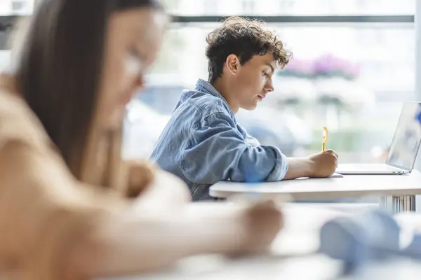 Pensive Smart Teenage Boy Using Laptop Taking Notes Learning Language — Stock fotografie