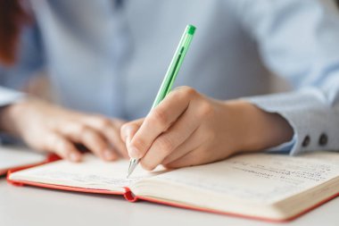 Kadın elinin not defterine not aldığı yakın plan, seçici odaklanma. Öğrenci, öğrenim dili, sınav, eğitim kavramı 