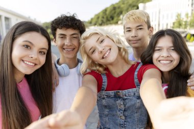 Bir grup gülümseyen, çok kültürlü genç selfie çekiyor ve sokak kameralarına bakıyor. Genç nüfuzlu biri arkadaşlarıyla birlikte video kaydediyor. Yaz konsepti 