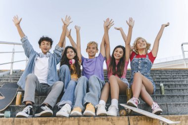 Bir grup mutlu arkadaş, renkli tişörtlü gençler ve kızlar yaz tatilini el ele tutuşarak kutluyorlar. 