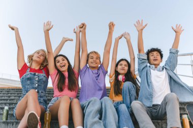 Renkli tişörtlü kızlar ve oğlanlar gülümsüyor. El ele tutuşuyorlar, buluşuyorlar, yaz tatili, kutlama yapıyorlar. Kent caddesinde çok ırklı bir grup çocuk var. Arkadaşlık kavramı
