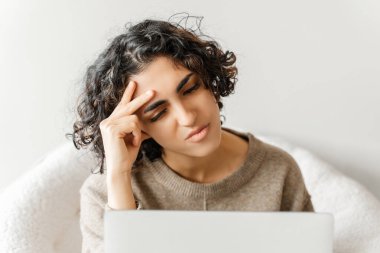 Diz üstü bilgisayar kullanarak bilgi toplayan stresli ortadoğulu kadın evde internet üzerinden çalışıyor. Ciddi bir öğrenci okuyor, dil öğreniyor, baş ağrısı çekiyor. Eğitim kavramı