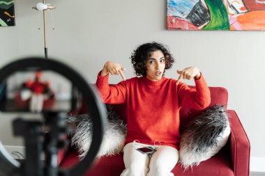 Neşeli genç kadın blogcu paylaşım için video içeriği hazırlıyor. Kadın kendini akıllı telefondan kaydediyor, parmaklarını hareket ettiriyor, konuşuyor. 