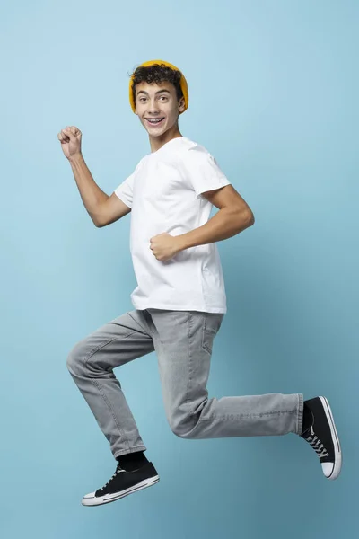 Porträtt Leende Pojke Med Gul Hatt Hoppa Isolerad Blå Bakgrund — Stockfoto