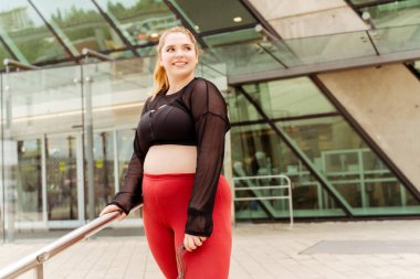 Eğitimden önce ayakta durup ip atlayan gülümseyen genç bayan. Artı boyut modeli, motivasyon, eğitim