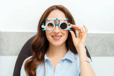 Göz doktorunun göz muayenesi, genç bayan için gözlük çerçevesi test ediyor. Sağlık, ilaç, insan konsepti