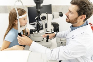 Gülümseyen kız modern klinikte göz muayenesi yapıyor. Sağlık hizmeti kavramı