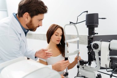 Klinikteki bir optometriste göz muayenesi yaptıran kadın hasta. Tıbbi muayene