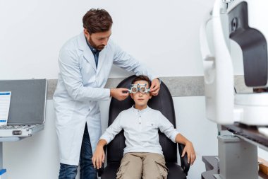 Erkek optometrist, küçük çocuğun optik görüntüsünü inceliyor. Sağlık, ilaç, tanı konsepti