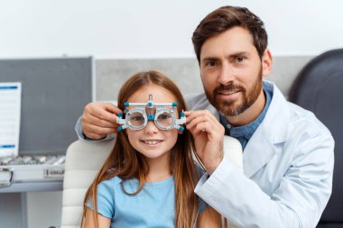 Erkek optometrist göz hekimliği kliniğindeki küçük bayan hastayı muayene ediyor. Sağlık, ilaç, tanı konsepti