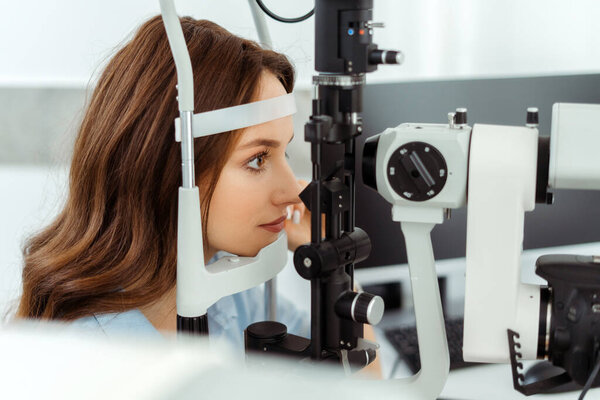 Happy lady doing eyesight measurement with optical slit lamp. Medical examination