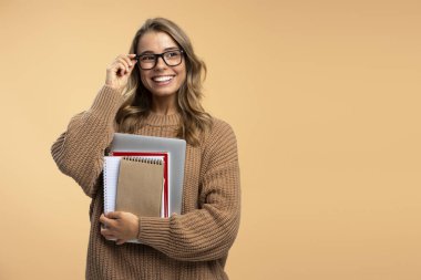 Zeki gülümseyen üniversite öğrencisi elinde dizüstü bilgisayar ve arka planda izole edilmiş kitaplar, fotokopi alanı, eğitim konsepti ile şık gözlükler takıyor. Güzel bir portre mutlu bir kadın, serbest çalışan başka tarafa bakıyor.