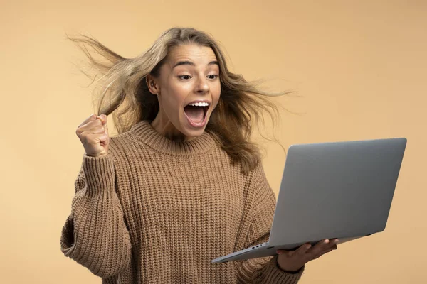 Young overjoyed woman holding laptop shopping online. Shopping, sale black Friday concept. Happy beautiful modern female using fast speed internet connection, celebration success innovation technology