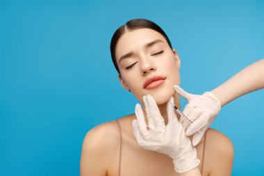 Güzel bir kadın yaşlanmayı önleyen iğne olurken gözlerini kapatıyor. Uzayı kopyala Mavi arka planda izole edilmiş. Güzellik bakımı, yaşlanma karşıtı prosedürler, estetik ameliyat konsepti.