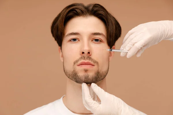 Junger Mann Besucht Kosmetikerin Mit Gesichtsfüller Vereinzelt Auf Beigem Hintergrund — Stockfoto