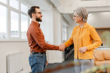 Gülümseyen, kendine güvenen iş adamları modern ofiste el sıkışırlar. Toplantı, takım çalışması, başarılı bir anlaşma. İş görüşmesi konsepti 
