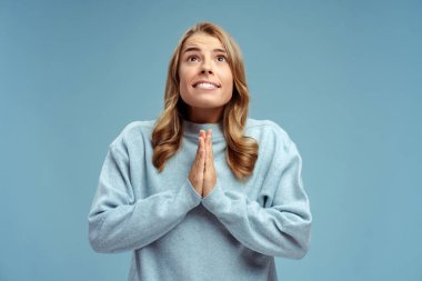 Çekici, pozitif bir kadının portresi, Hıristiyan dua ediyor, bir şey diliyor, yukarı bakıyor, mavi arka planda tek başına duruyor. Din kavramı