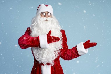 Mavi arka planda elleri olan komik Aziz Nicholas ya da Noel Baba, kar. Kış tatili kavramı 