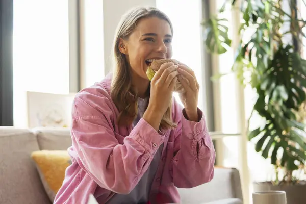 現代のカフェで座っているハンバーガーを食べるかわいい魅力的な空腹の女性 美味しいフードコンセプト — ストック写真
