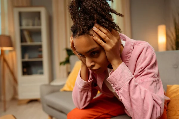 頭痛を持つアフリカ系アメリカ人女性を動揺させた肖像画は 自宅の部屋に座っている悪いニュースを受け取った 病気の女性は片頭痛を持っています 健康コンセプト — ストック写真